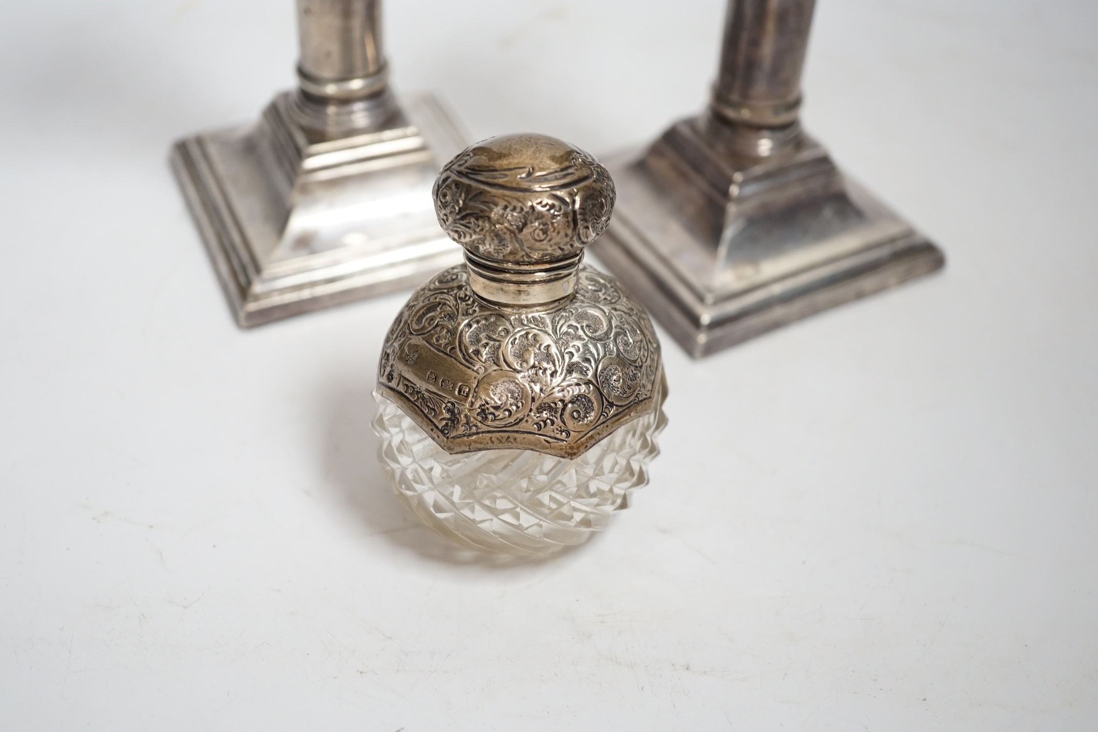 A pair of modern silver mounted candlesticks, 17cm, weighted, together with an Edwardian silver mounted cut glass scent bottle.